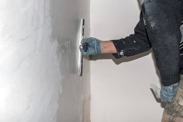 istock The hands of a worker level the walls with a spatula using putty during repairs. 1366073573