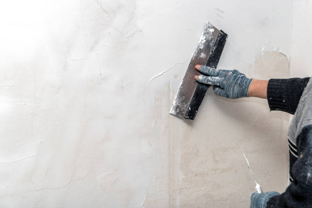 istock The hands of a worker level the walls with a spatula using putty during repairs. 1366073584