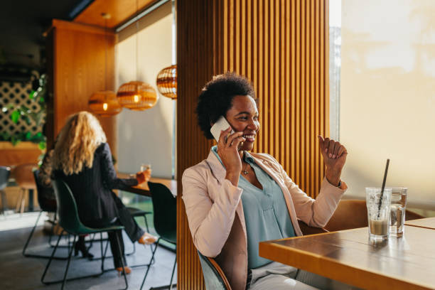 istock Smiling african woman talking on phone at cafe 1366074451