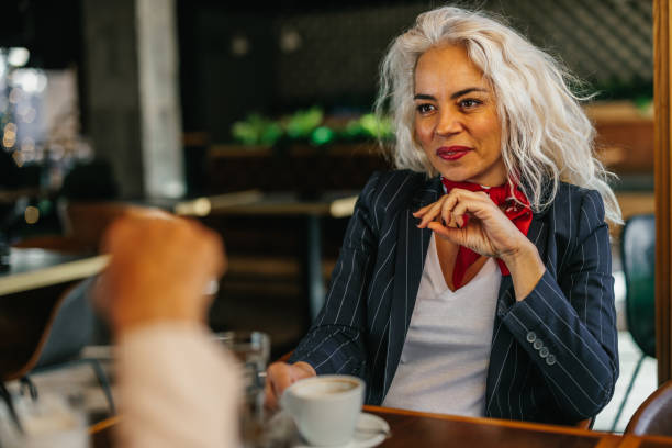 istock Beautiful woman sitting with unrecognized friend at cafe 1366074466
