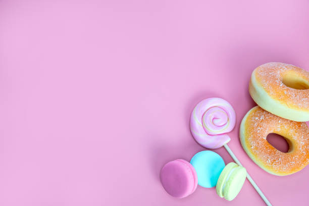 istock Candy sweets concept. Pink lollypop and donuts, macarons on pink background, copy space top view 1366075763