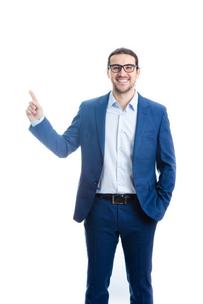 istock Confident businessman pointing up forefinger smiling isolated on white background. Contented business person, wearing eyeglasses, determined shows index finger upwards 1366076876