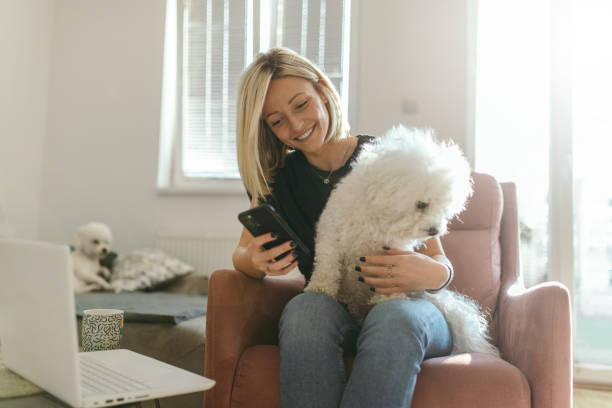 istock Young woman using mobile phone with her dog at home 1366077157