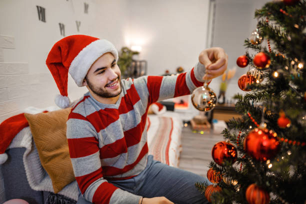 istock Young men decorating Christmas tree in the living room 1366078341