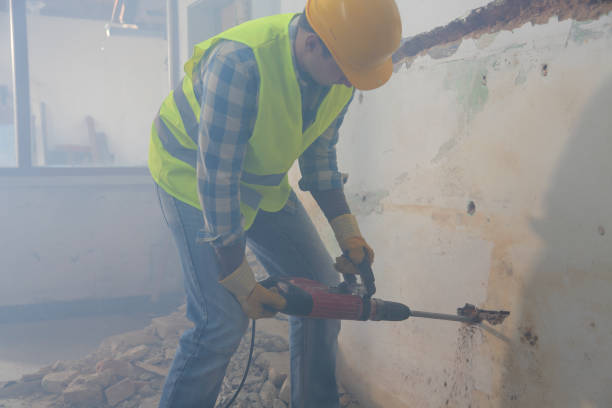 Young worker making holes in the wall for electric installation in an old apartment.
