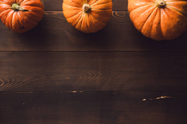 istock Three pumpkins on a brown wood. Flatlay. Copy space 1366083427