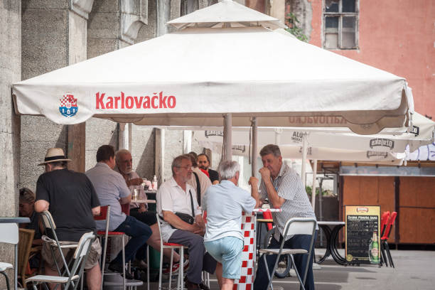 zagreb, croacia - 20 de junio de 2021: ancianos mayores, amigos, croatas, discutiendo en una multitud en la terraza de un bar restaurante en verano en la capital croata, zagreb. - kafa fotografías e imágenes de stock