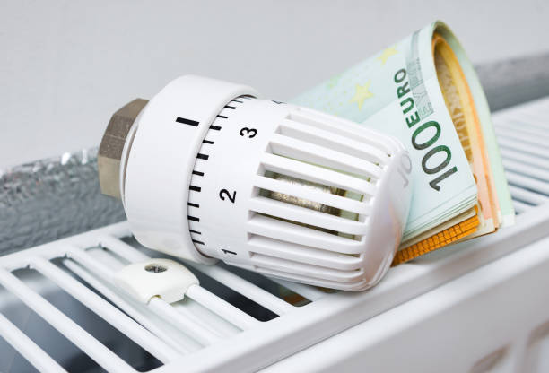 Thermostat with money on a radiator heating . stock photo
