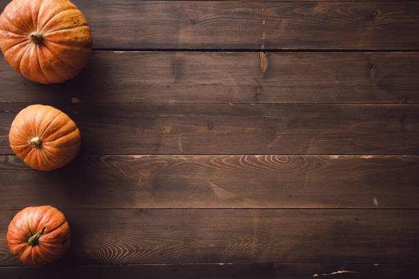 istock Three pumpkins on a brown wood. Copy space 1366087507