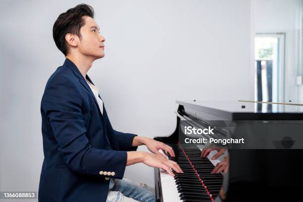 A Confident Man Wearing Blue Suit And Jean Sitting On The Chair And Playing Grand Piano With White Background Looking Forward Musician Play Melody Portrait And Lifestyle Concept Stock Photo - Download Image Now