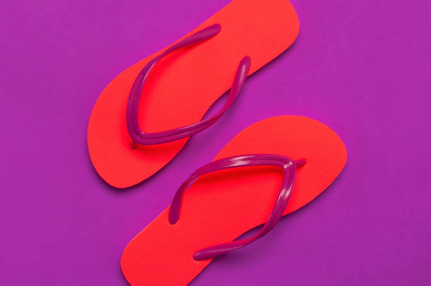 istock Coral flip flops on purple background. Flat lay, top view, copy space. Creative Summer Vacation travel Background. Women's summer footwear. Bright flip flops, trend colors 1366091966