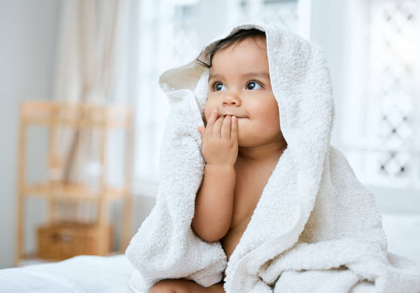 aufnahme eines entzückenden babys, das nach dem baden mit einem handtuch bedeckt ist - baby stock-fotos und bilder