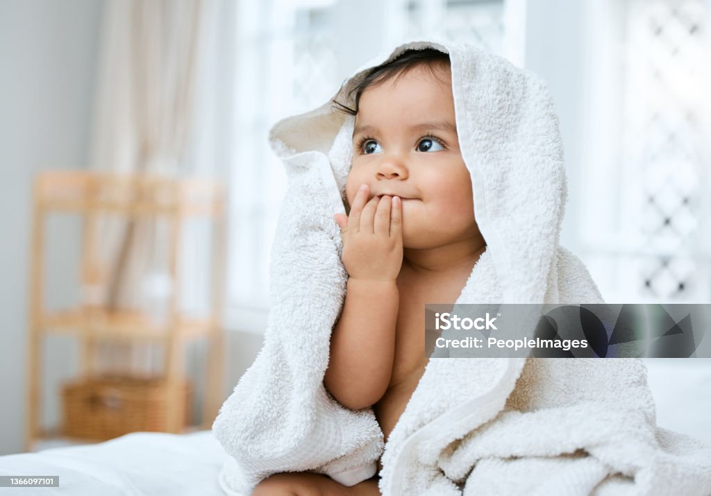 Shot of an adorable baby covered in a towel after bath time I taste so fresh Baby - Human Age Stock Photo