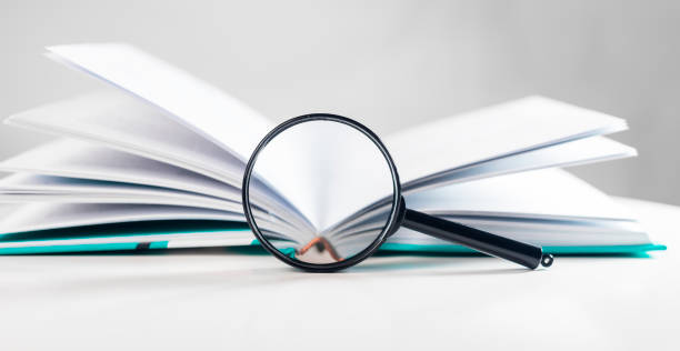 istock Magnifying glass over open business book. Concept of knowledge and getting information 1366098490