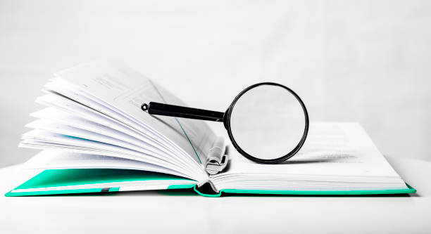 istock Magnifier over open business paper book. Concept of knowledge and studying 1366098496