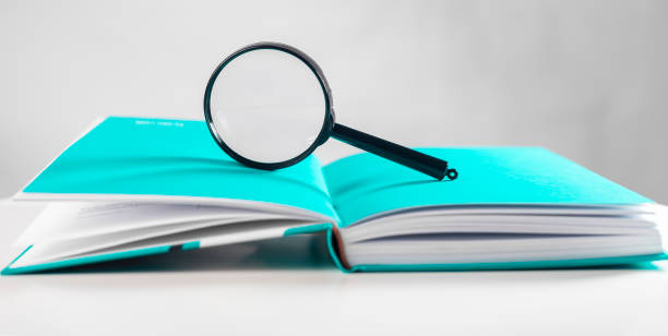 istock Magnifier over open bright paper book. Concept of knowledge 1366099068