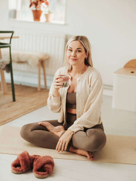 Woman on yoga mat before/after practise with coffee tea stock photo
