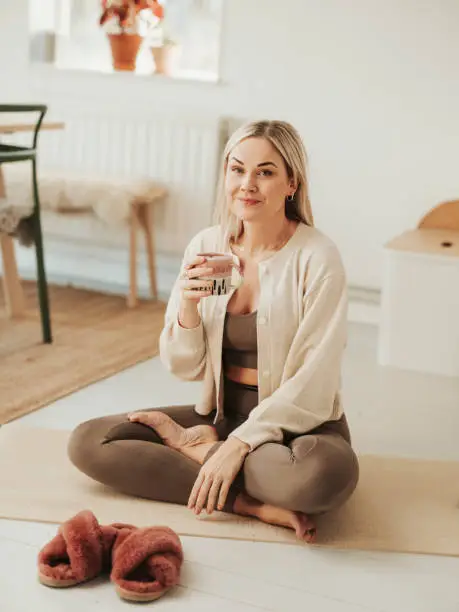 Woman on yoga mat before/after practise watching with coffee tea
Photo taken indoors of mid adult woman with minimal retoushing, i neverchange body shape.