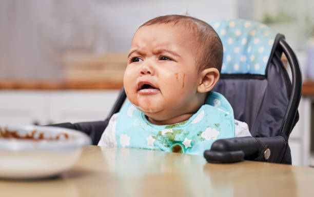 istock Shot of a baby crying while eating a meal 1366104428