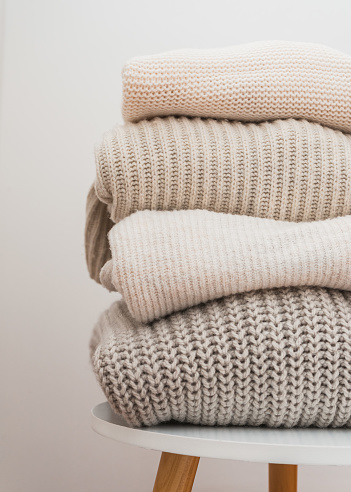 Pile of folded cozy knitted cardigan sweaters