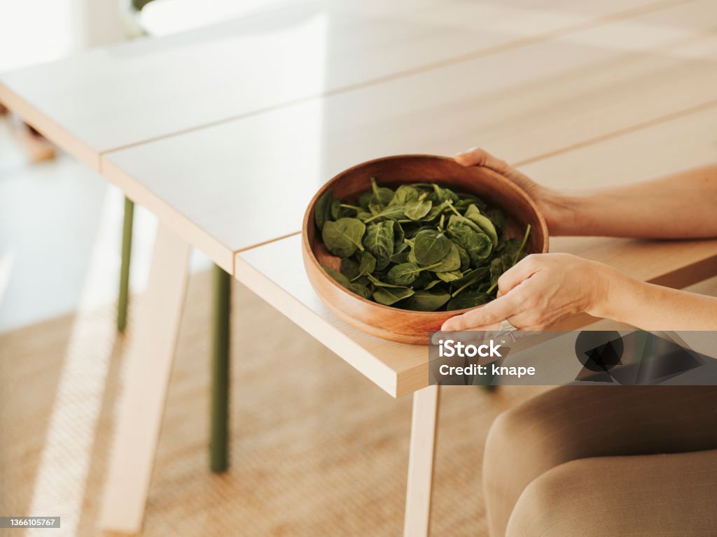 Bowl of spinach on table with womens hand bowl of spinach on table with womens hand
Photo taken indoors in kitchen of healthy food Adult Stock Photo
