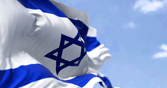 Detail of the national flag of Israel waving in the wind on a clear day. Democracy and politics. Patriotism. Selective focus.
