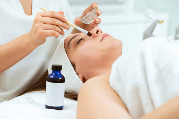 istock Cosmetologist brushes beauty serum on woman's face 1366106158