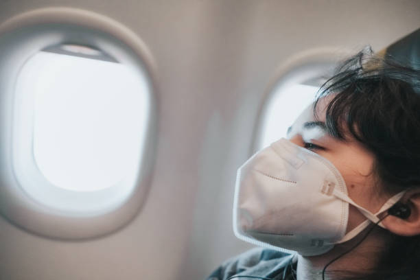istock girl with face mask in plane at window seat sleeping 1366108601