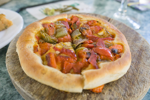 Coca - traditional Catalan savory cake, similar to pizza with baked sweet green and red pepper, fried tomato and onion