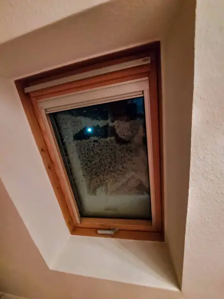 The full moon shines through a snow-covered skylight