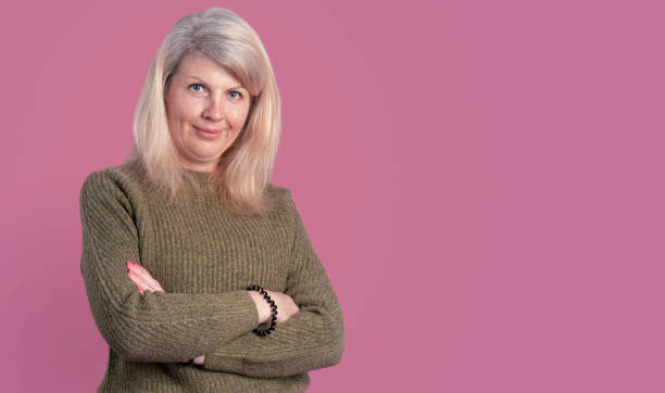 istock Smiling woman with crossed arms in pink studio 1366115583