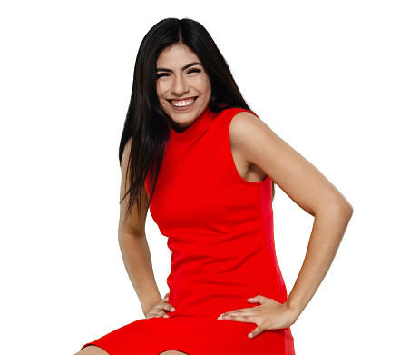 One person of aged 20-29 years old who is beautiful with long hair latin american and hispanic ethnicity female standing in front of white background wearing dress who is shouting and celebrating
