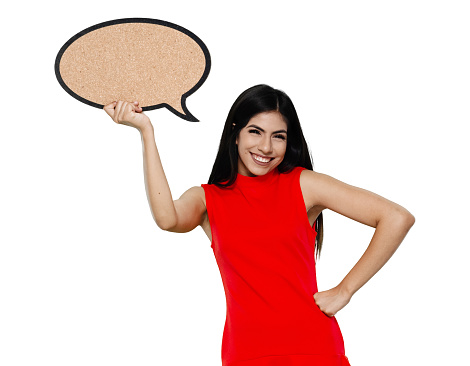Waist up of aged 20-29 years old who is beautiful with black hair latin american and hispanic ethnicity young women standing in front of white background wearing dress who is asking and holding speech bubble with copy space