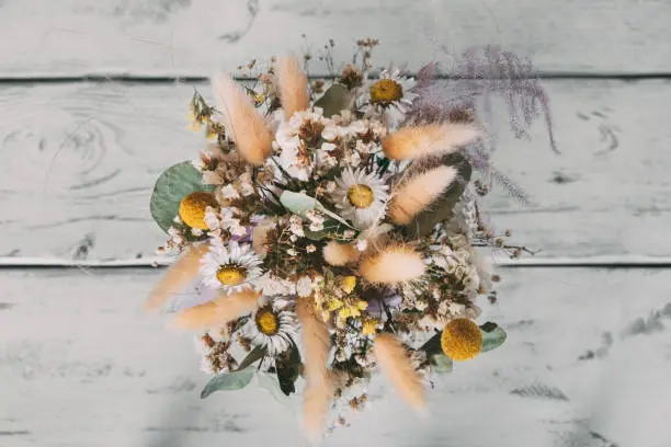 Top view of bouquet of dried flowers on white wooden table. Beautiful bouquet for interior.