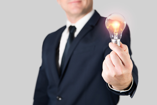 Man in jacket showing a lighted light bulb. Concept of idea, motivation, inspiration and success