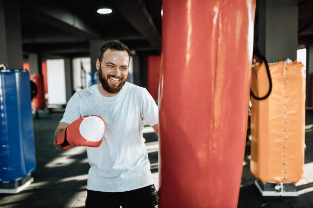 istock Smiling Male Spending Last Strength On Heavy Bag Workout In Gym 1366125416