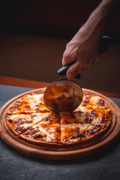 istock Cutting a freshly baked margherita  pizza with a pizza cutter 1366127632