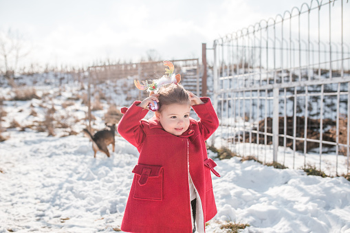 Beautiful, little girl dressed in a red coat enjoying the snow and winter magic.