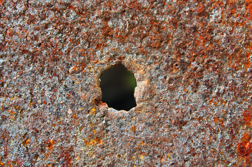 A burnt hole in a rusty iron sheet. Close-up. Background. Texture.