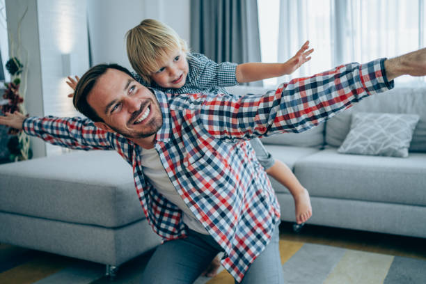 pai e filho pequeno em casa. - braços no ar - fotografias e filmes do acervo