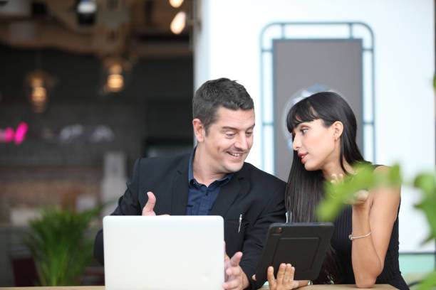 istock two young business people working and communicating while standing at the office with city building background. 1366138690