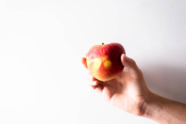 istock A hand holding an apple against white background. 1366139229