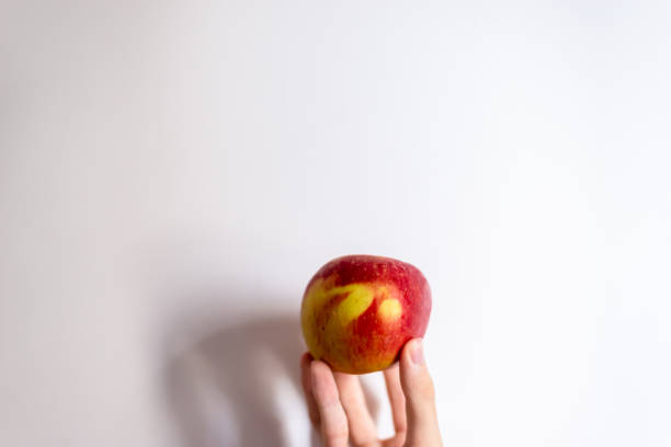 istock A hand holding an apple against white background. 1366139255