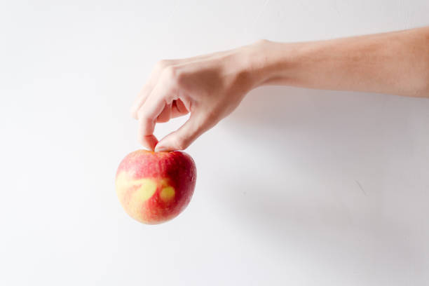 istock A hand holding an apple against white background. 1366139257