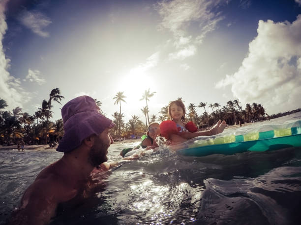 istock Father playing with his daughters in the ocean. 1366140110