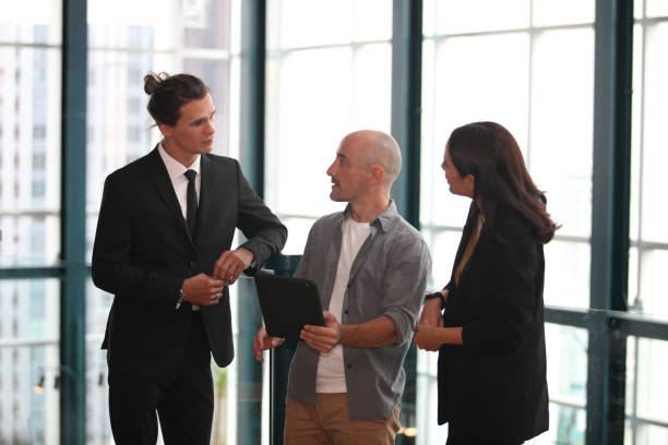 istock team young business people working and communicating while standing at the office with city building background. 1366141011