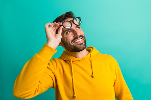 Happy young male in casual sweatshirt and eyeglasses holds his head