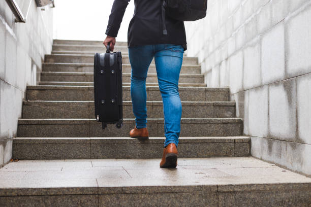 istock White young businessman going up the stairs while carrying a suitcase and wearing a backpack 1366146381