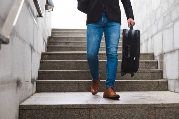 istock White young businessman going down the stairs while carrying a digital tablet and a suitcase and wearing a backpack 1366146382