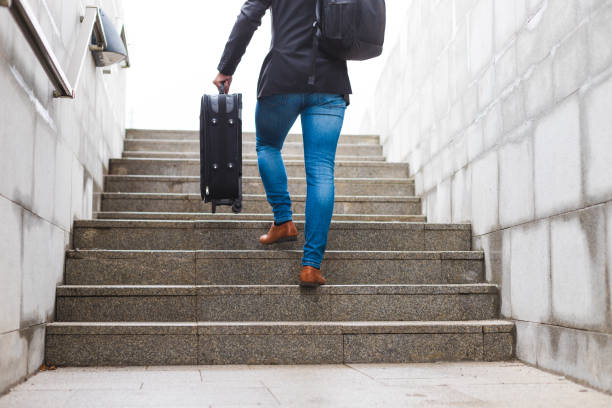 istock White young businessman going up the stairs while carrying a suitcase and wearing a backpack 1366146388